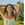 Woman with arms raised in a field with trees in the background
